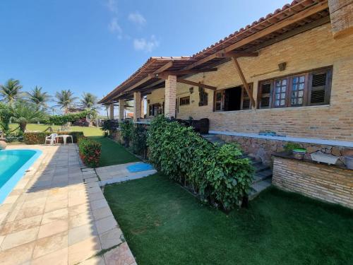 a house with a garden and a swimming pool at Villa Sirena Pousada de charme in Beberibe