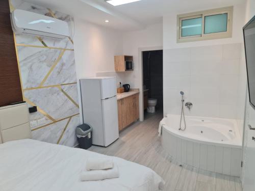 a white bathroom with a bath tub and a bed at Vida Bhermon 3 , 2 suites in Majdal Shams