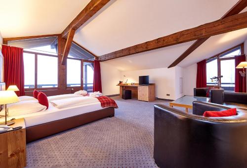 a bedroom with a large bed and a living room at Hotel Schillingshof in Bad Kohlgrub