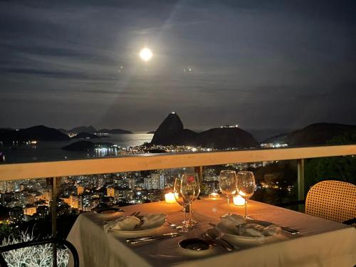 a table with wine glasses and a view of the moon at Vila Santa Teresa in Rio de Janeiro