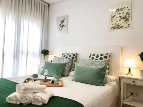 Schlafzimmer mit einem Bett mit grünen und weißen Kissen in der Unterkunft Apto2 Céntrico Frentebahía Garaje Incluido in Castro-Urdiales