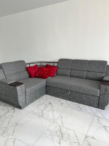 um sofá com almofadas vermelhas sentado num piso de mármore em New Marine Apartment em Yuzhne