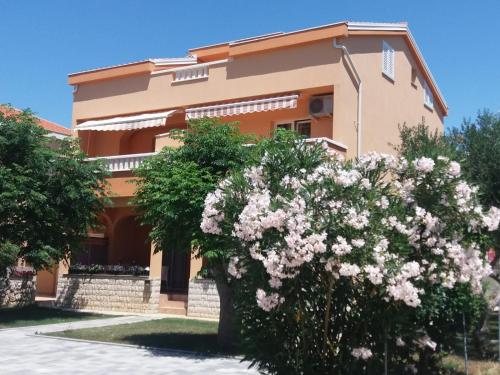 a house with pink flowers in front of it at Apartmani Ruža in Novalja