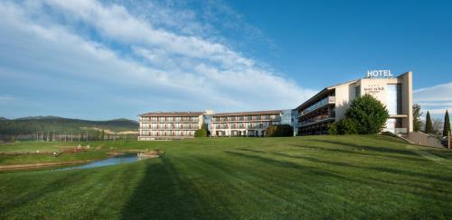 a building on a grassy hill next to a building at Hotel Mas Solà in Santa Coloma de Farners