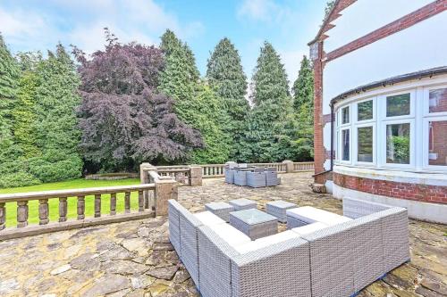 a patio with a couch and a fence and trees at Exquisite Manor House in Surrey Hills in Lower Kingswood