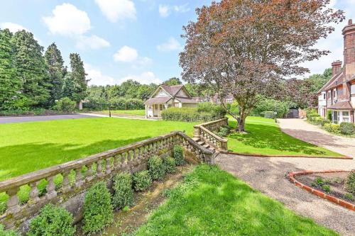 posiadłość z kamiennym płotem oraz podwórko z trawą i drzewami w obiekcie Exquisite Manor House in Surrey Hills w mieście Lower Kingswood