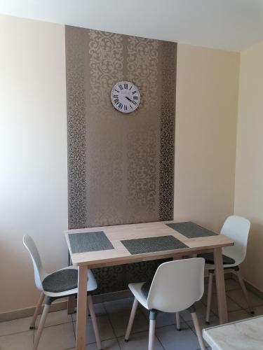 a table with chairs and a clock on a wall at Szamóca Apartman in Szeged