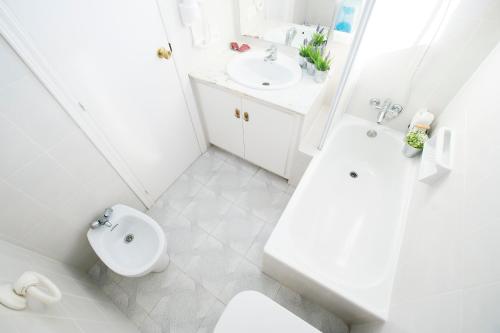 a white bathroom with a toilet and a sink at Hotel Canada in Benicàssim