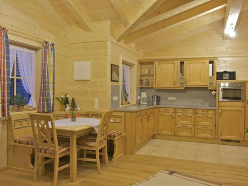 eine Küche mit Holzschränken sowie einem Tisch und Stühlen in der Unterkunft Ferienwohnungen Bauregger - Chiemgau Karte in Inzell