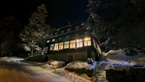 a building with lights on in the snow at night at Hotel Děvín in Pec pod Sněžkou