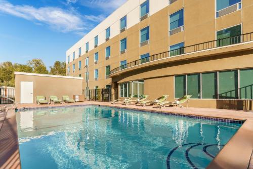 a swimming pool with chairs and a building at Holiday Inn Express & Suites Oakhurst-Yosemite Park Area, an IHG Hotel in Oakhurst