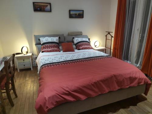 um quarto com uma cama grande com lençóis e almofadas vermelhas em LES PINGOUINS DE LA MARNE em Le Perreux-Sur-Marne