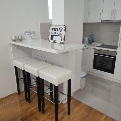 a kitchen with a counter with stools with a sign on it at Stan na dan Bijeljina Niki in Bijeljina