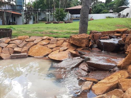 a rock retaining wall with a pond in a yard at Pousada da Estação in Brotas