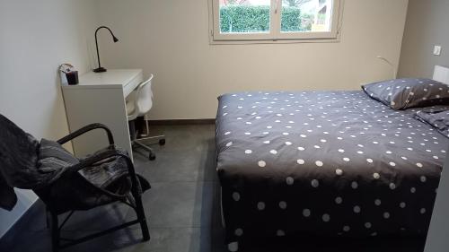 een slaapkamer met een bed, een bureau en een stoel bij Chez Anne Marie in Beausemblant