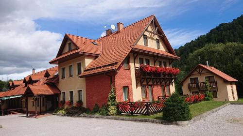 a large house with red flowers in front of it at Penzion pod Vlkolíncom in Ružomberok