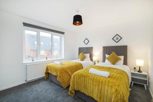 2 camas en una habitación blanca con mantas amarillas en Lovely 2 bed Apartment with Parking in Thurrock, en South Ockendon