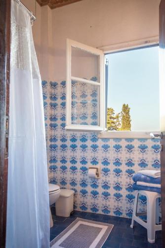 a bathroom with a toilet and a window at Corfu Country House in Vitalades