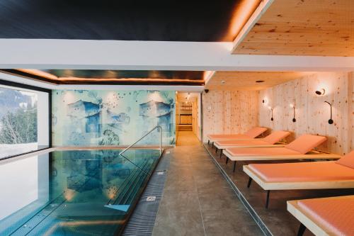 a room with a swimming pool and some benches at Alpin - Studios & Suites in Warth am Arlberg