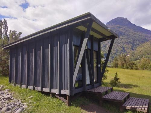 a small black building with benches in a field at Base Puelo in Cochamó