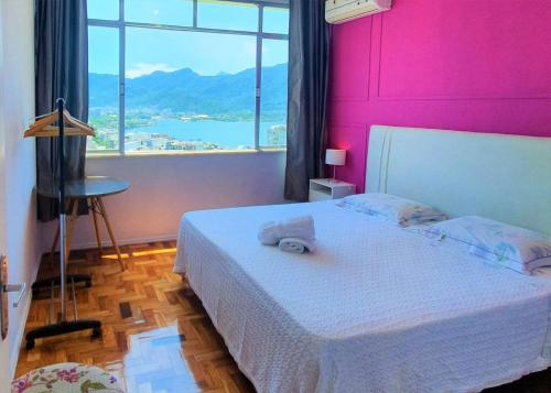 a bedroom with a white bed with a pink wall at Mar, Lagoa, Vista Incrível em Ipanema in Rio de Janeiro