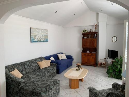 un salon avec un canapé bleu et une table dans l'établissement Apartments Pahljina, à Rab
