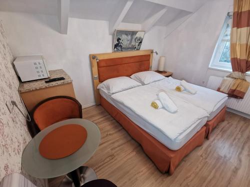 Dormitorio pequeño con cama y mesa en Pension Föhrenhain, en Gerasdorf bei Wien