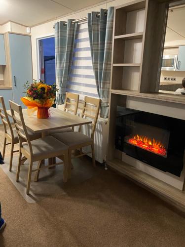 uma sala de jantar com uma mesa e uma lareira em holidayhome-romneysands holiday park em Littlestone-on-Sea