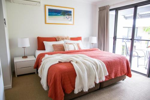 um quarto com uma cama com um cobertor laranja em Tropical Getaway in 2 Bedroom Unit in 4 star Resort em Noosaville