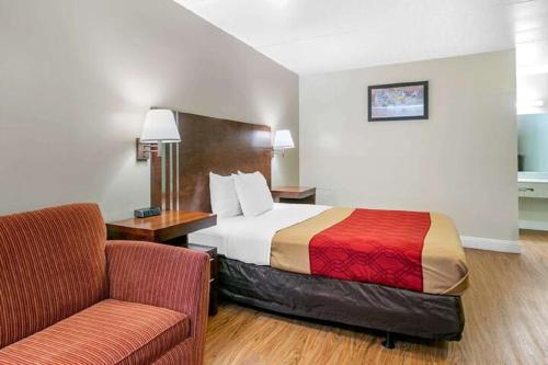 a hotel room with a bed and a chair at King's Inn Motel in Reading