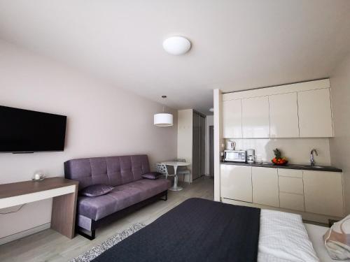 salon z fioletową kanapą i kuchnią w obiekcie Apartament Czarna Góra TIGNES 4 Sienna w mieście Sienna