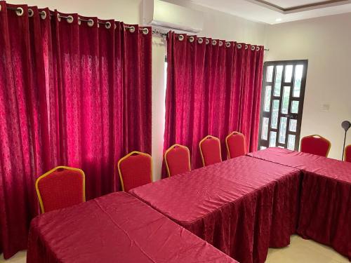 a room with red curtains and a table and chairs at HOTEL LES ARCADES in Abomey-Calavi