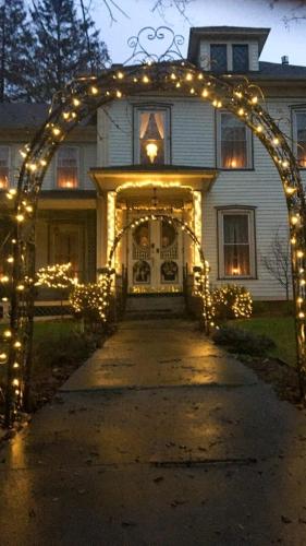 an arch with christmas lights in front of a house at Raindrops On Roses Bed & Breakfast in Herkimer