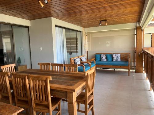 a dining room with a table and chairs and a couch at Apto novo Imperia Lounge pé-na-areia Itacimirim in Itacimirim