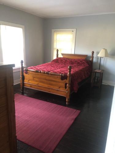 a bedroom with a wooden bed with a red bedspread at Private Cottage in Rural Setting in Clemmons