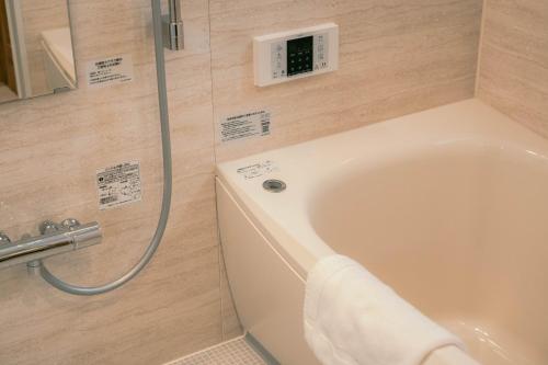 a bath tub in a bathroom with a shower at 7 Rooms Hotel & Cafe - 30mins from Disneyland in Tokyo
