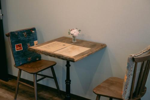 a table with a vase of flowers on it with two chairs at 7 Rooms Hotel & Cafe - 30mins from Disneyland in Tokyo