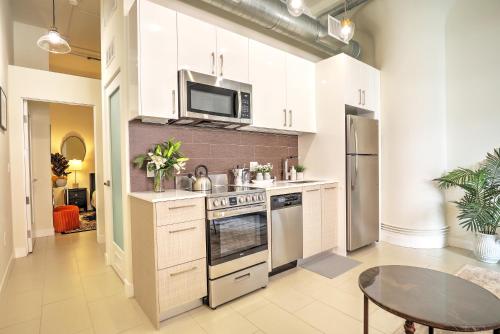 a kitchen with white cabinets and a stove and a table at Classic Los Angeles Elegance in Downtown, Sleeps 4, Free Parking and 360 Degree View Roof Top Pool! in Los Angeles