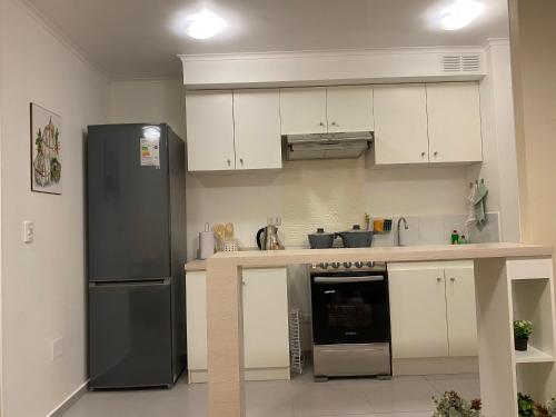 a kitchen with a black refrigerator and white cabinets at Refugio Los Volcanes. in Osorno