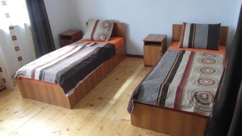 two beds in a room with wooden floors at Gvirilas Sakhli Guest House in Khashuri