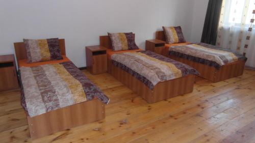 3 camas en una habitación con suelo de madera en Gvirilas Sakhli Guest House, en Khashuri