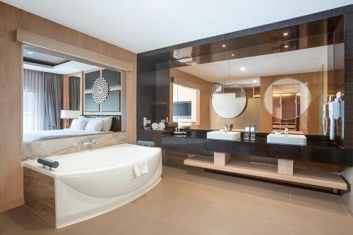 a bathroom with a tub and two sinks and a bed at Swiss-Belhotel Manokwari in Manokwari