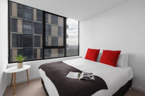 a bedroom with a bed with red pillows and a window at Resort Style Living In the Heart of Moonee Ponds in Melbourne
