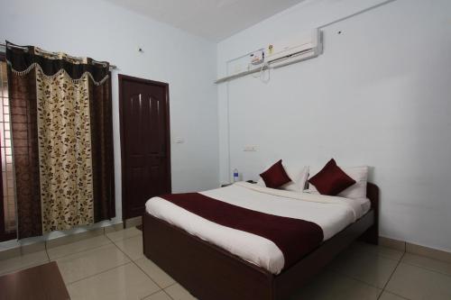 a bedroom with a large bed with red pillows at Lakshana Service Apartment - Big Temple Thanjavur in Thanjāvūr