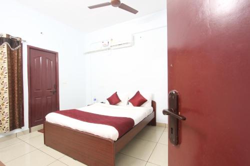 a bedroom with a bed and a red door at Lakshana Service Apartment - Big Temple Thanjavur in Thanjāvūr