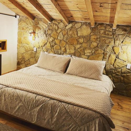 a bed in a room with a stone wall at Cabañas Boutique Villaseñor Pet and 420 Friendly in Huasca de Ocampo
