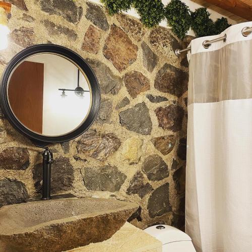 a bathroom with a mirror and a stone wall at Cabañas Boutique Villaseñor Pet and 420 Friendly in Huasca de Ocampo
