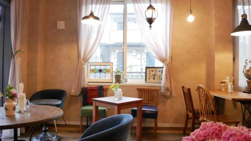 a restaurant with tables and chairs and a window at 7 Rooms Hotel & Cafe - 30mins from Disneyland in Tokyo
