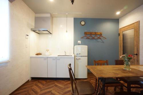 a kitchen and dining room with a table and a refrigerator at 7 Rooms Hotel & Cafe - 30mins from Disneyland in Tokyo