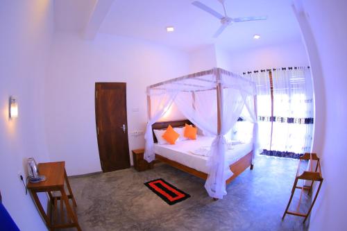 a bedroom with a canopy bed with orange pillows at Abinu"s Place in Dickwella